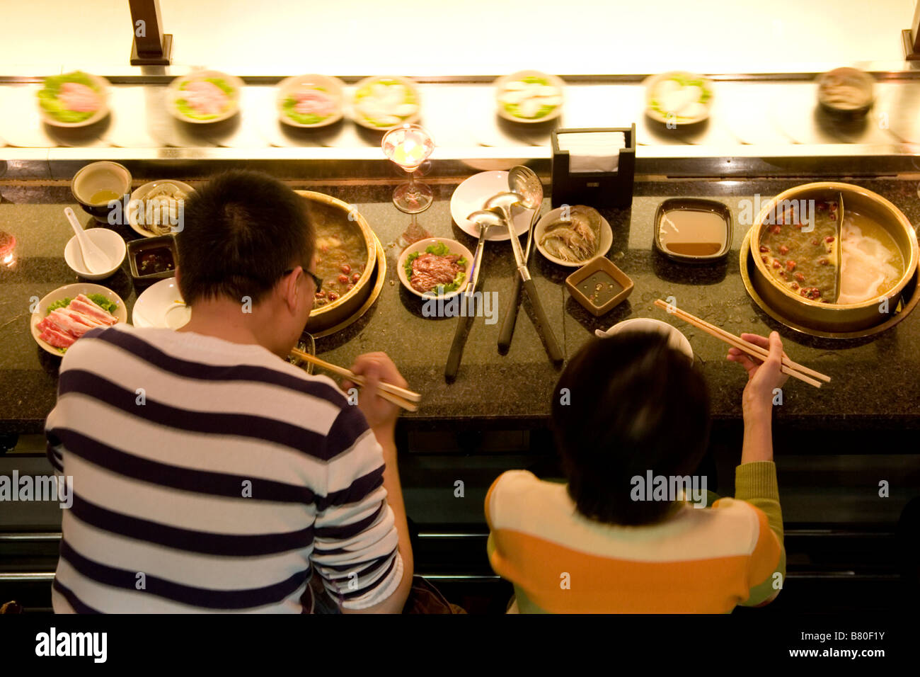 Platten-Zug in einem modernen Hotpot Restaurant in Chengdu in Sichuan in China. Stockfoto
