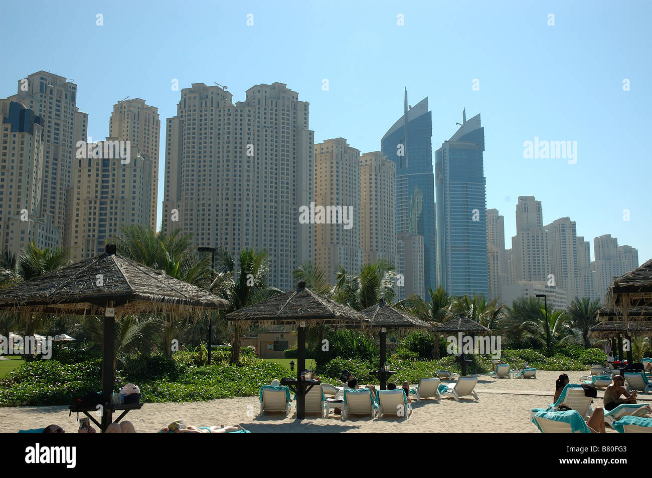 Sonne Badegäste, Jumeirah Beach, Dubai, Vereinigte Arabische Emirate, Naher Osten. Mit hohen Gebäuden im Hintergrund Stockfoto