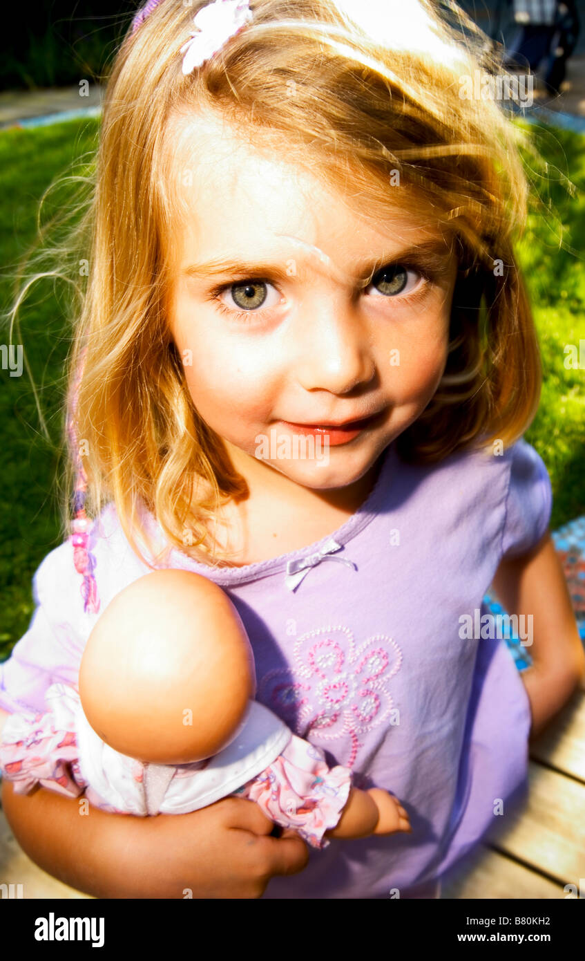 kleines Mädchen hält Babydoll glücklich Stockfoto