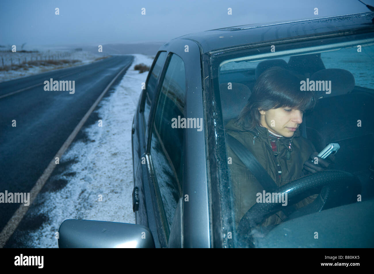 Eine junge Frau bittet um Hilfe, wenn ihr Auto eine an einem Wintertag in den Cambrian Mountains Powys Mid Wales Großbritannien Panne Stockfoto