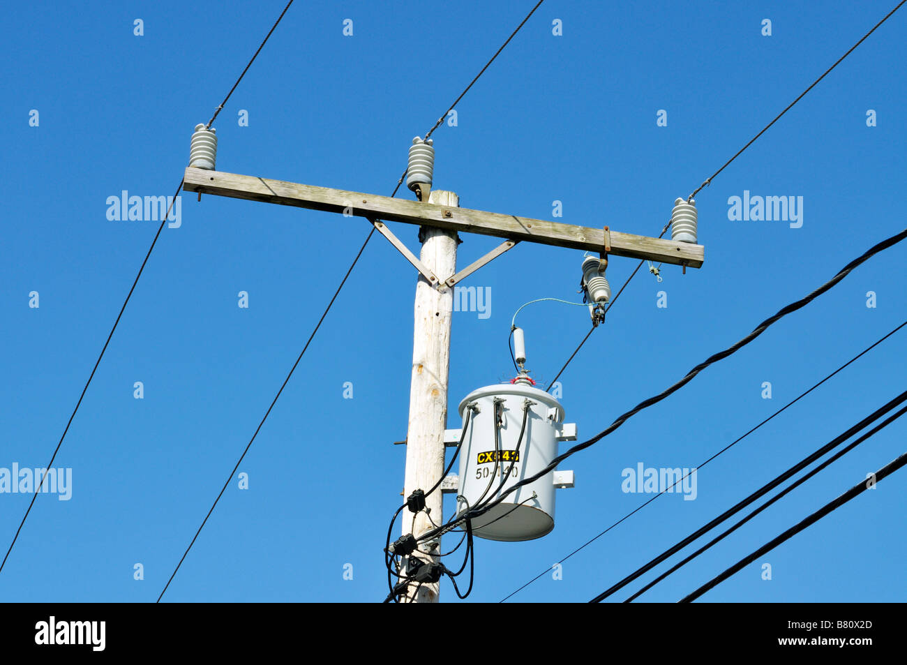 Einzigen elektrischen Transformator auf Holz Telefonmast zeigt Elektrokabel und Isolatoren gegen blauen Himmel Stockfoto