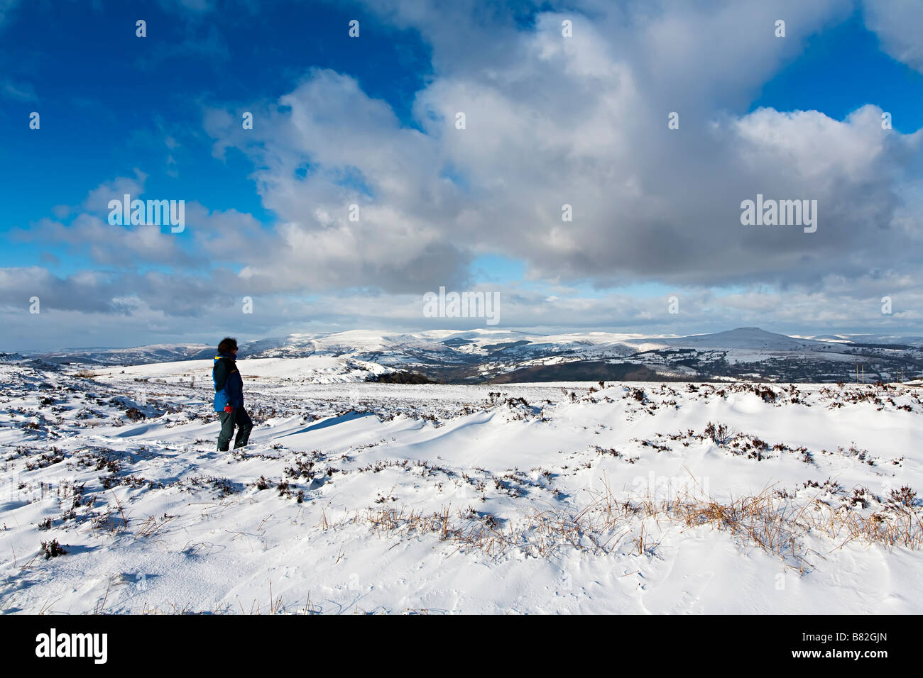 Frau, die im Blick auf die schwarzen Berge im Winter Wales UK Stockfoto