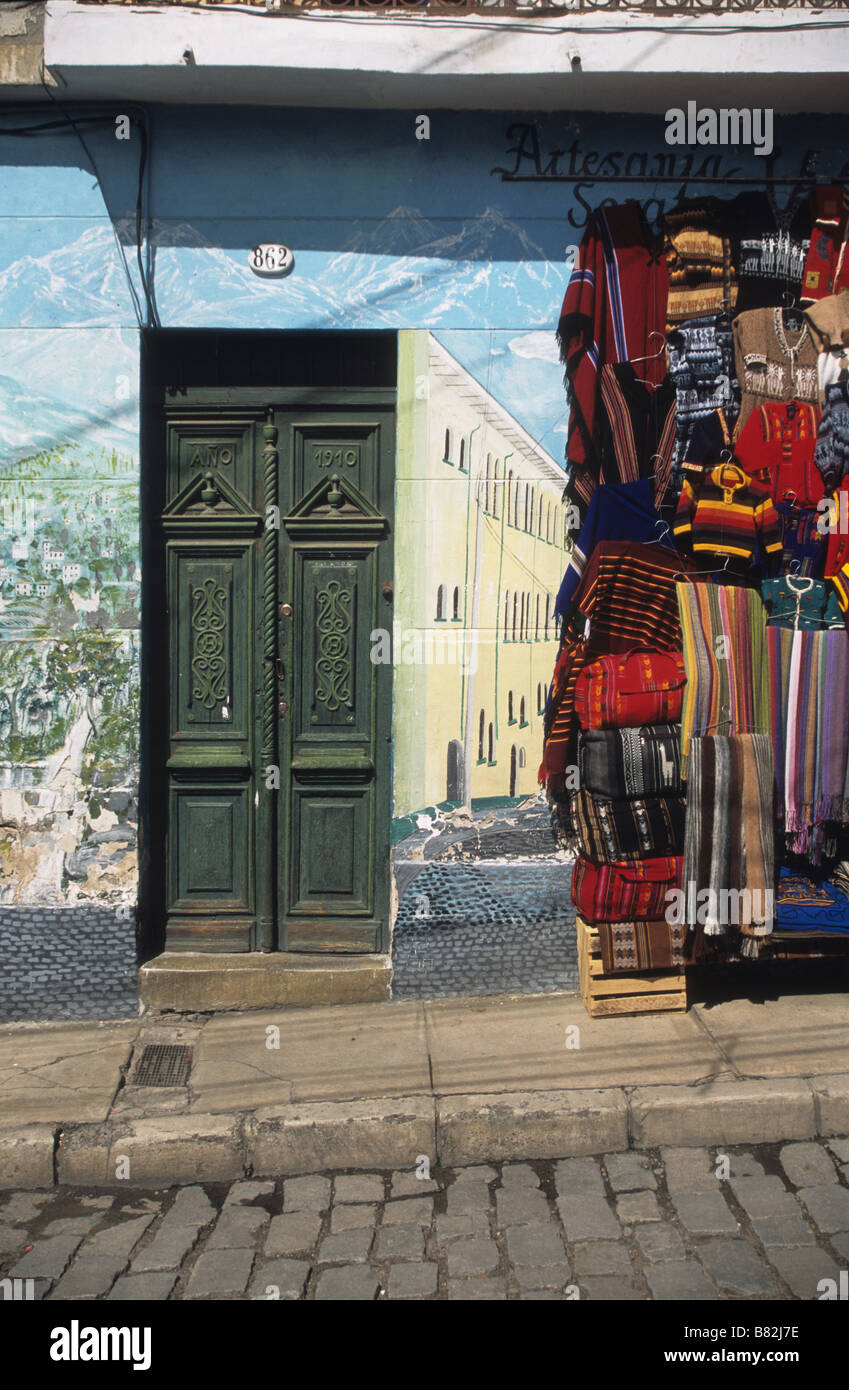 Alte Holztür, Wandgemälde und Textilien hängen draußen im Handwerksmarkt, Calle Linares, La Paz, Bolivien Stockfoto