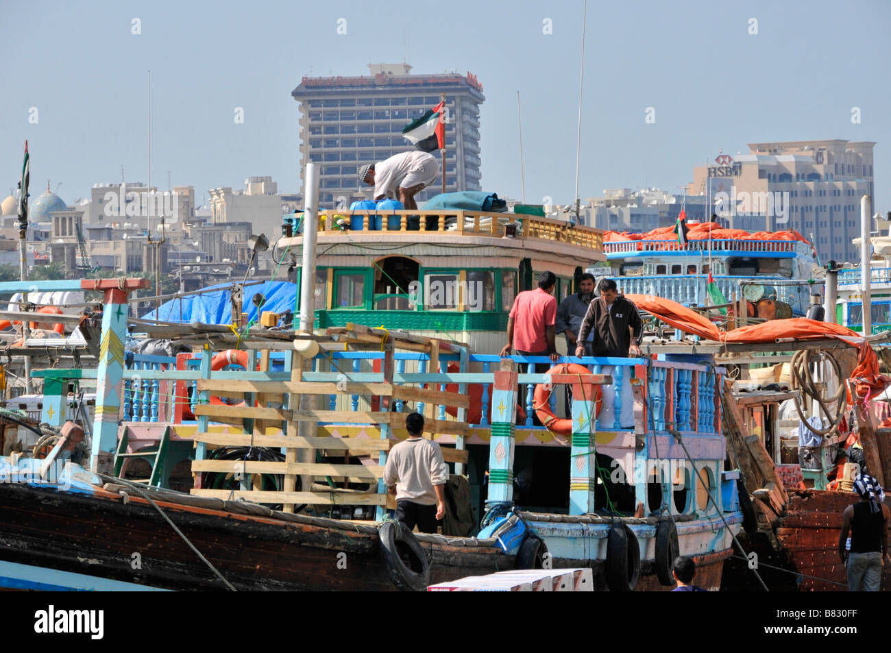 Dubai Creek Seeleute Arbeiter auf Dhow-Boot mit Fracht beladen & Merchandise auf überfüllten Hafenkai Vereinigte Arabische Emirate VAE Naher Osten Stockfoto