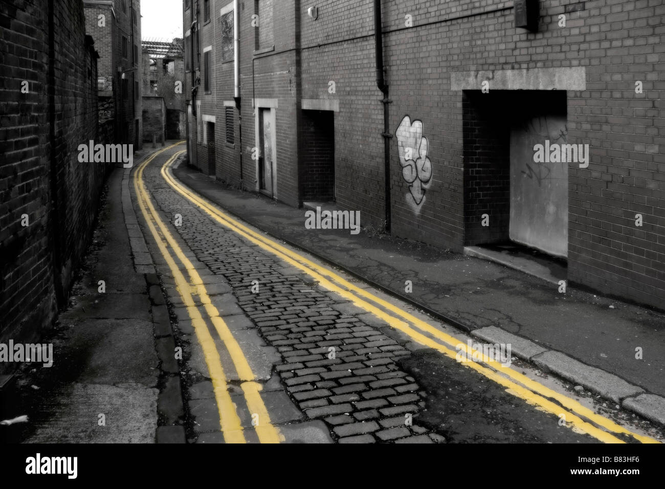 Doppelte gelbe Linien auf einer heruntergekommenen Seitenstraße in Bradford, West Yorkshire Stockfoto