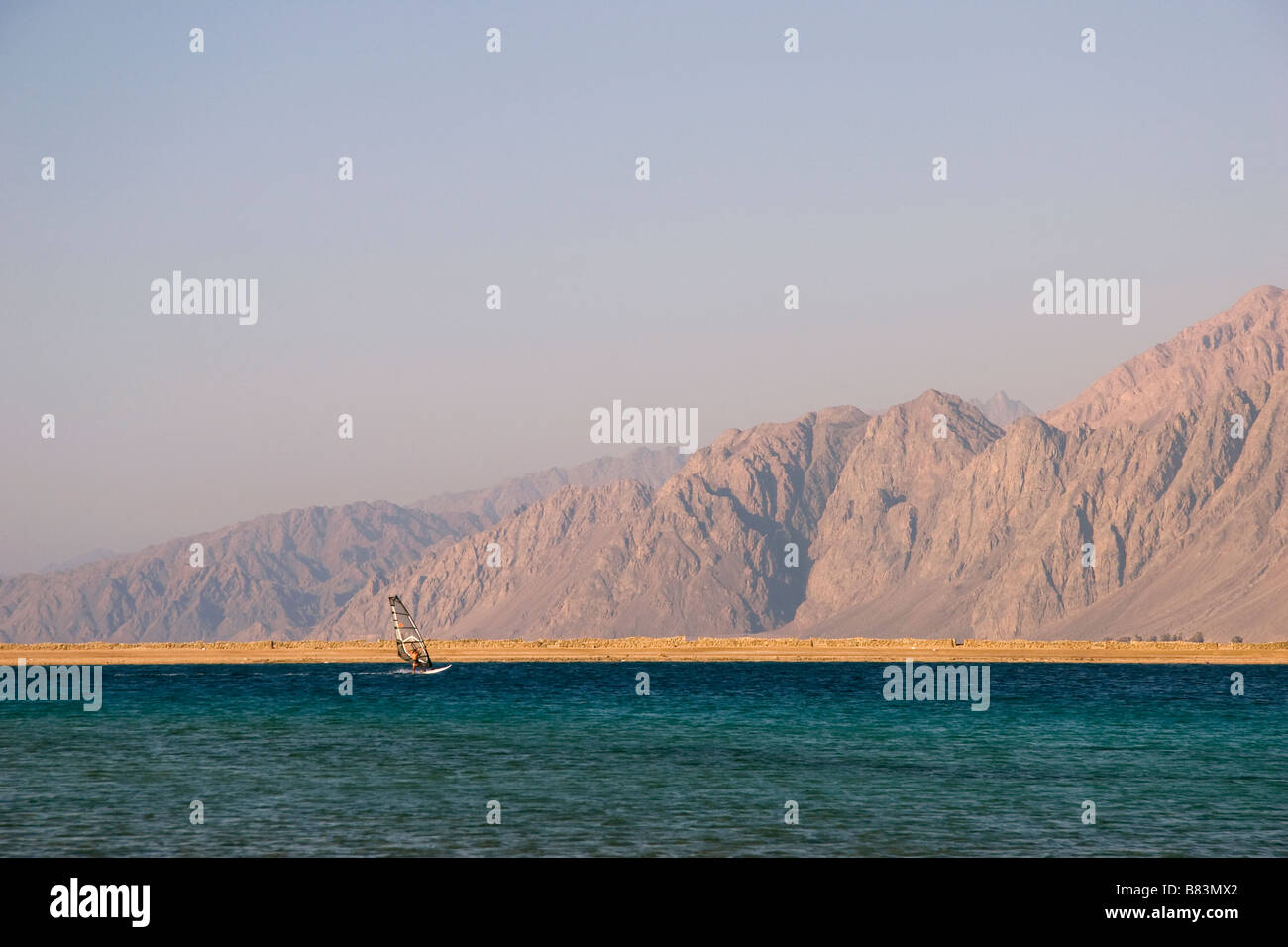 Ein Windsurfer überquert das türkisblaue Wasser in den Sand Landzunge Laguna Bay im Sinai Resort Dahab in Ägypten Stockfoto