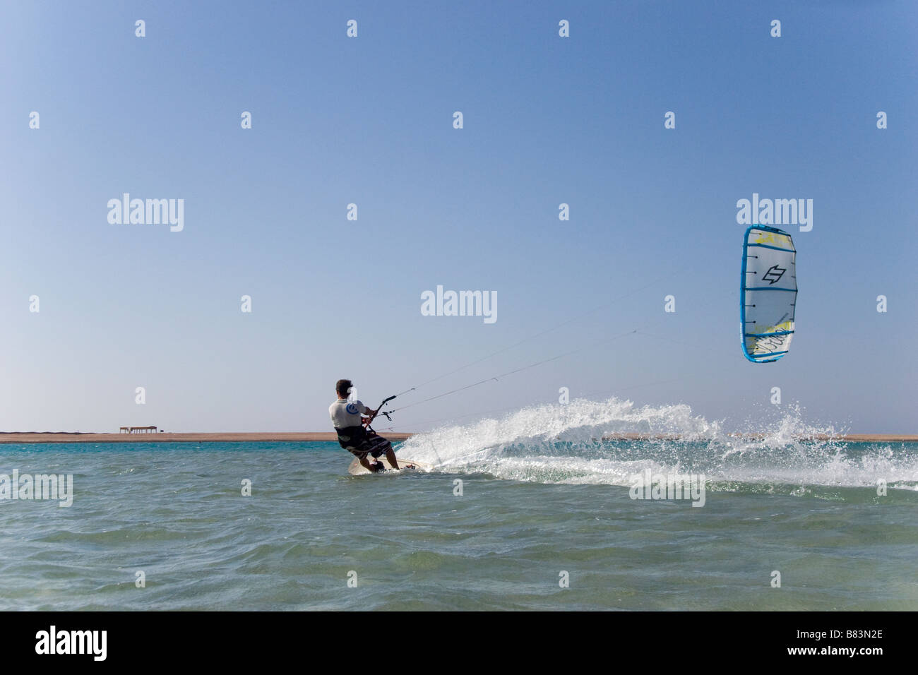 Ein Kitesurfer kreuzt die türkisfarbene Flachwasser-Lagune (Qura-Bucht) in den Sand spucken in den Sinai Resort Dahab in Ägypten Stockfoto