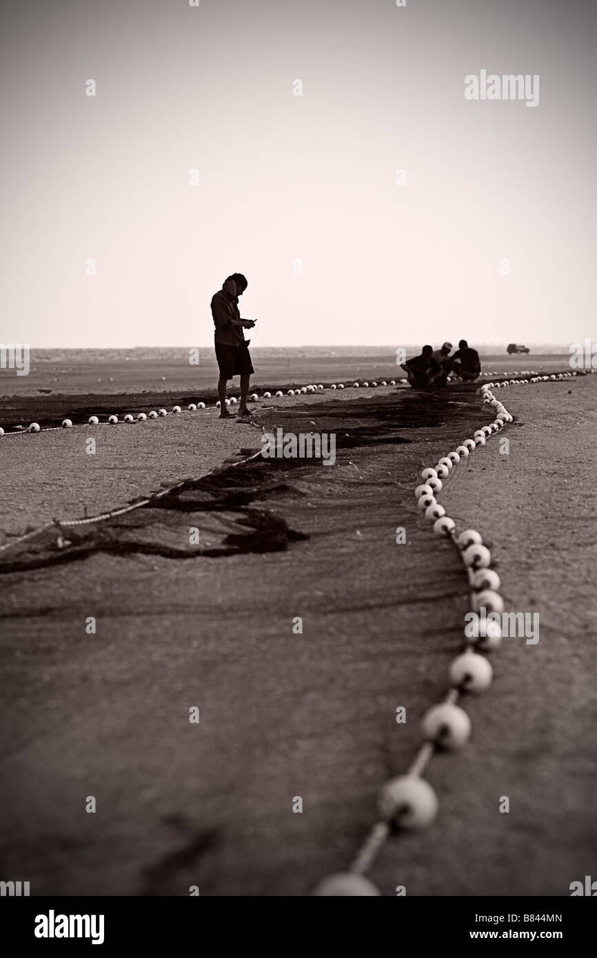 Arbeiter reparieren Fischernetze am Strand Stockfoto