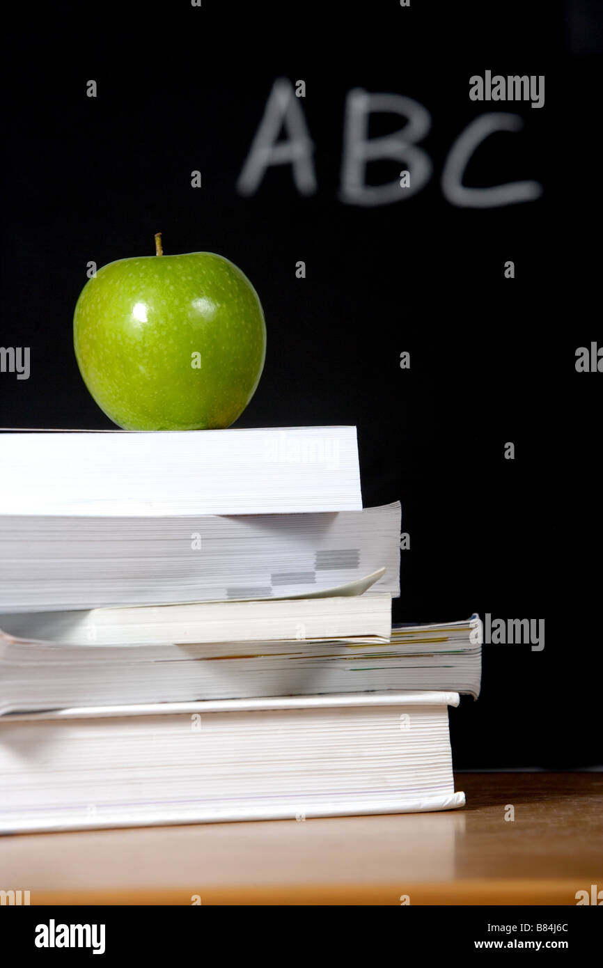 Ein Apfel auf einem Stapel Bücher auf dem Lehrer-Schreibtisch Stockfoto