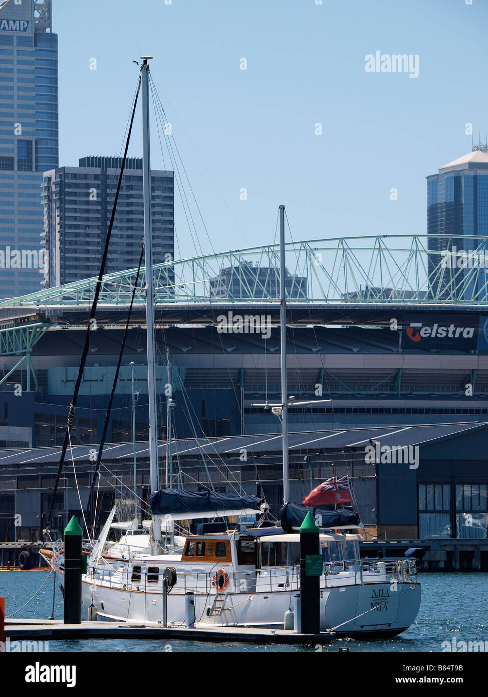 BOOT VOR ANKER IM DOCKLAND GEBIET VON MELBOURNE MIT TELSTRA DOME HINTER VICTORIA AUSTRALIEN Stockfoto