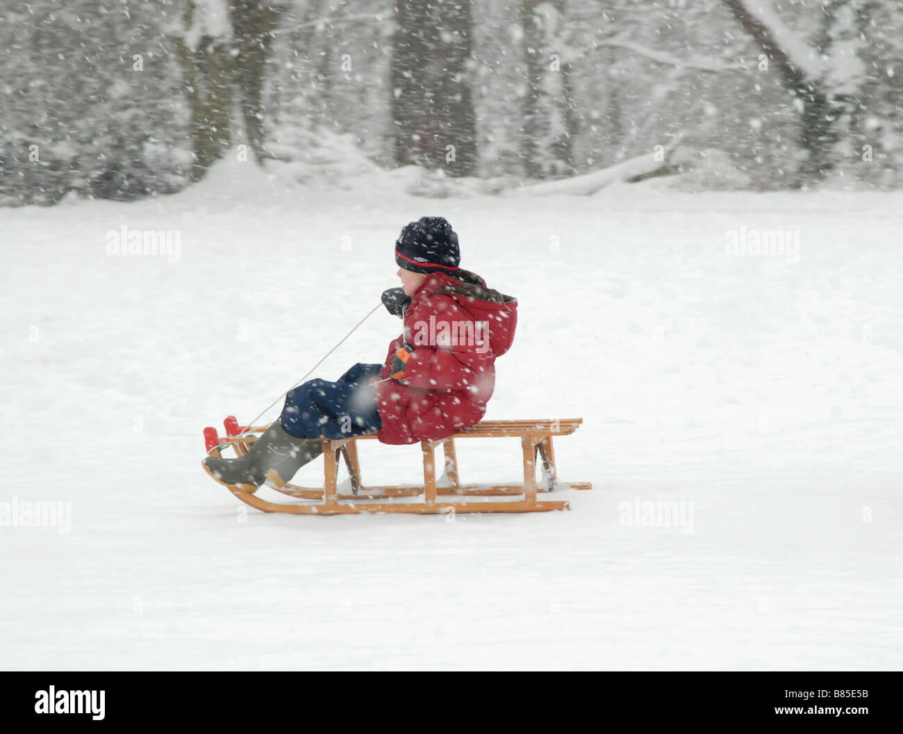 Winterspaß: kleiner Junge auf einem Schlitten in den Schnee, Cheam, Südlondon, Surrey, England Stockfoto