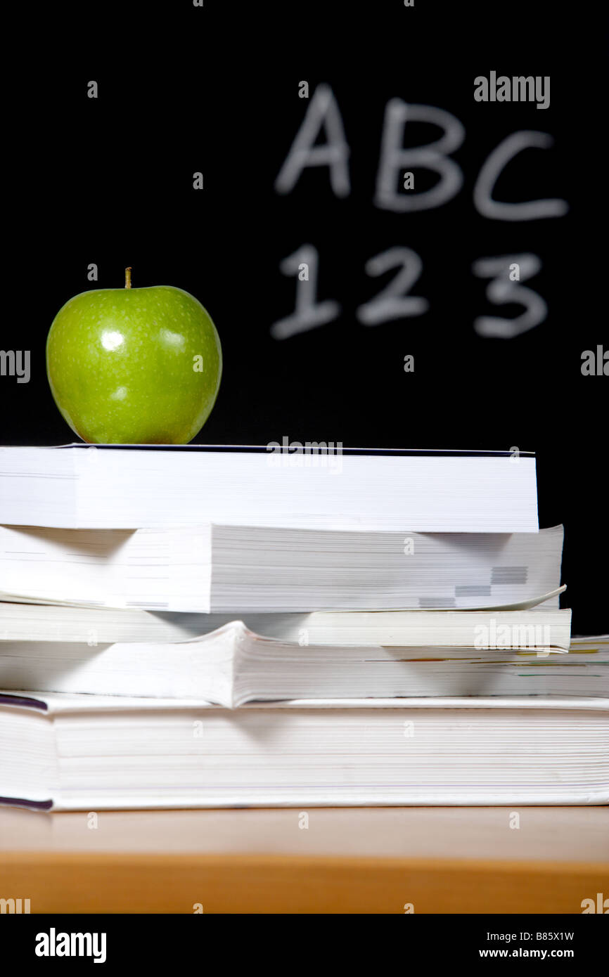 Ein Apfel auf einem Stapel Bücher auf dem Lehrer-Schreibtisch Stockfoto