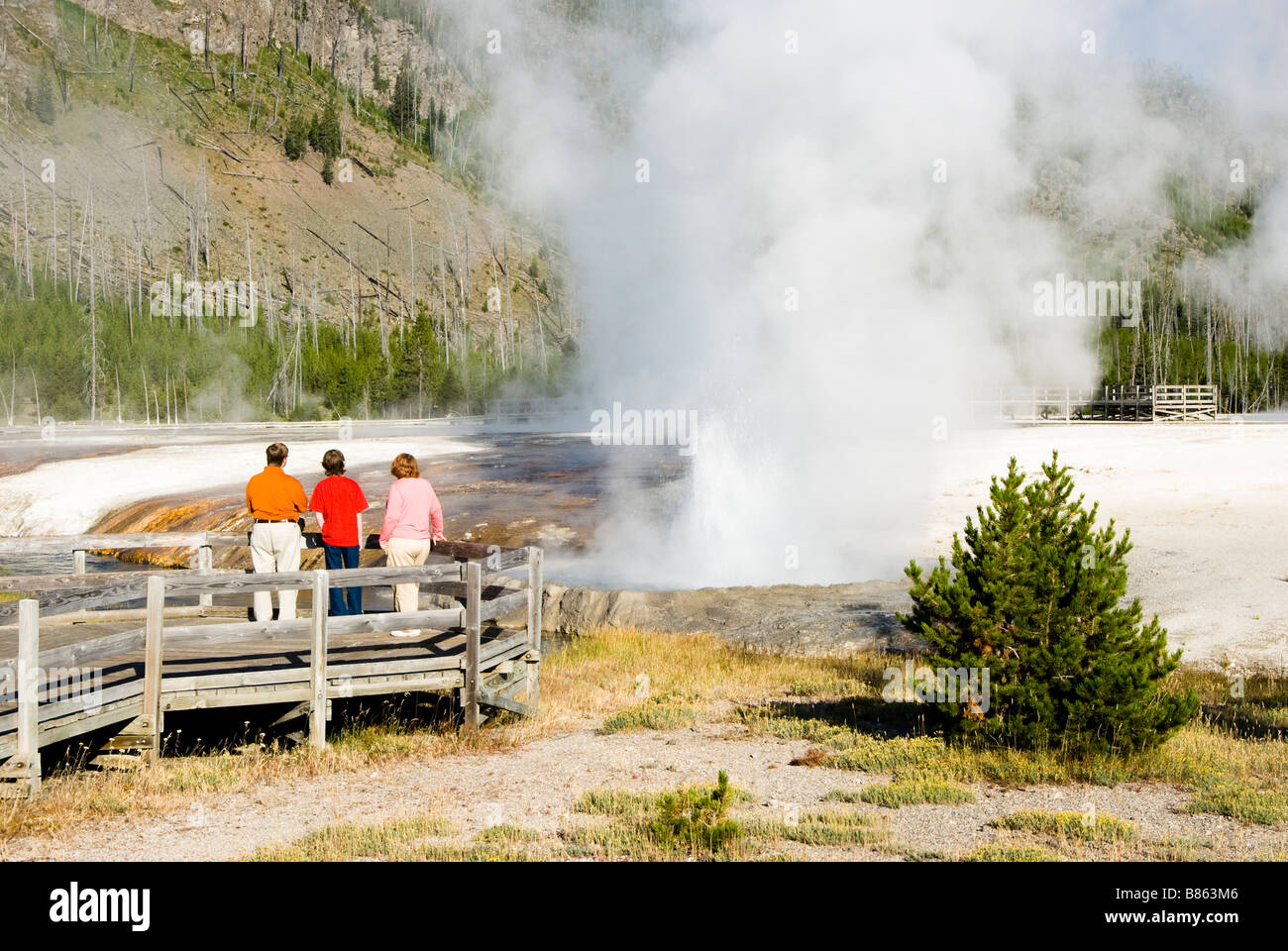 Touristen, die beobachten, wie ein Geysir bricht im Yellowstone National Park Stockfoto