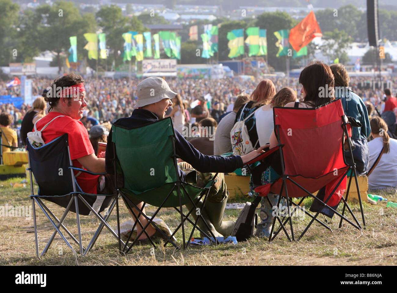 Eine Gruppe von Freunden genießen Sie die Sonne vor den Menschenmassen auf dem Glastonbury Festival in Pilton, Somerset in England. Stockfoto