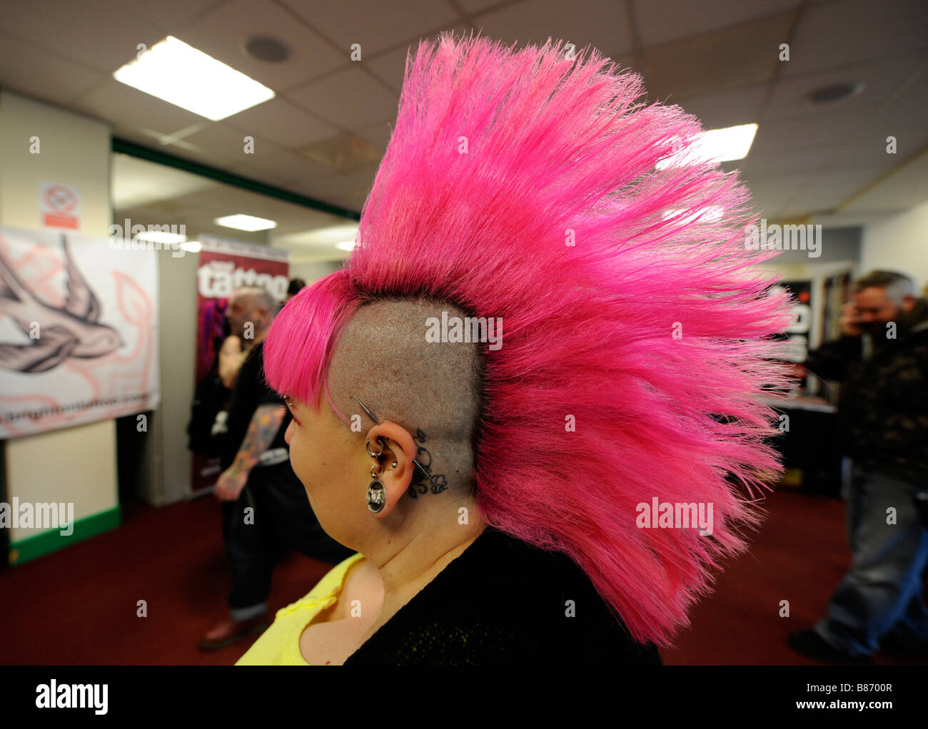 Junge Frau mit leuchtend rosa mohikanischen Haarschnitt auf der Brighton Tattoo Convention Stockfoto