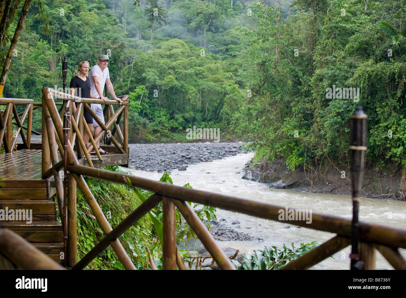 Mittelamerika, Costa Rica. Ein paar steht auf einer Terrasse mit Blick auf die Pacuare Fluss im Dschungel. Stockfoto