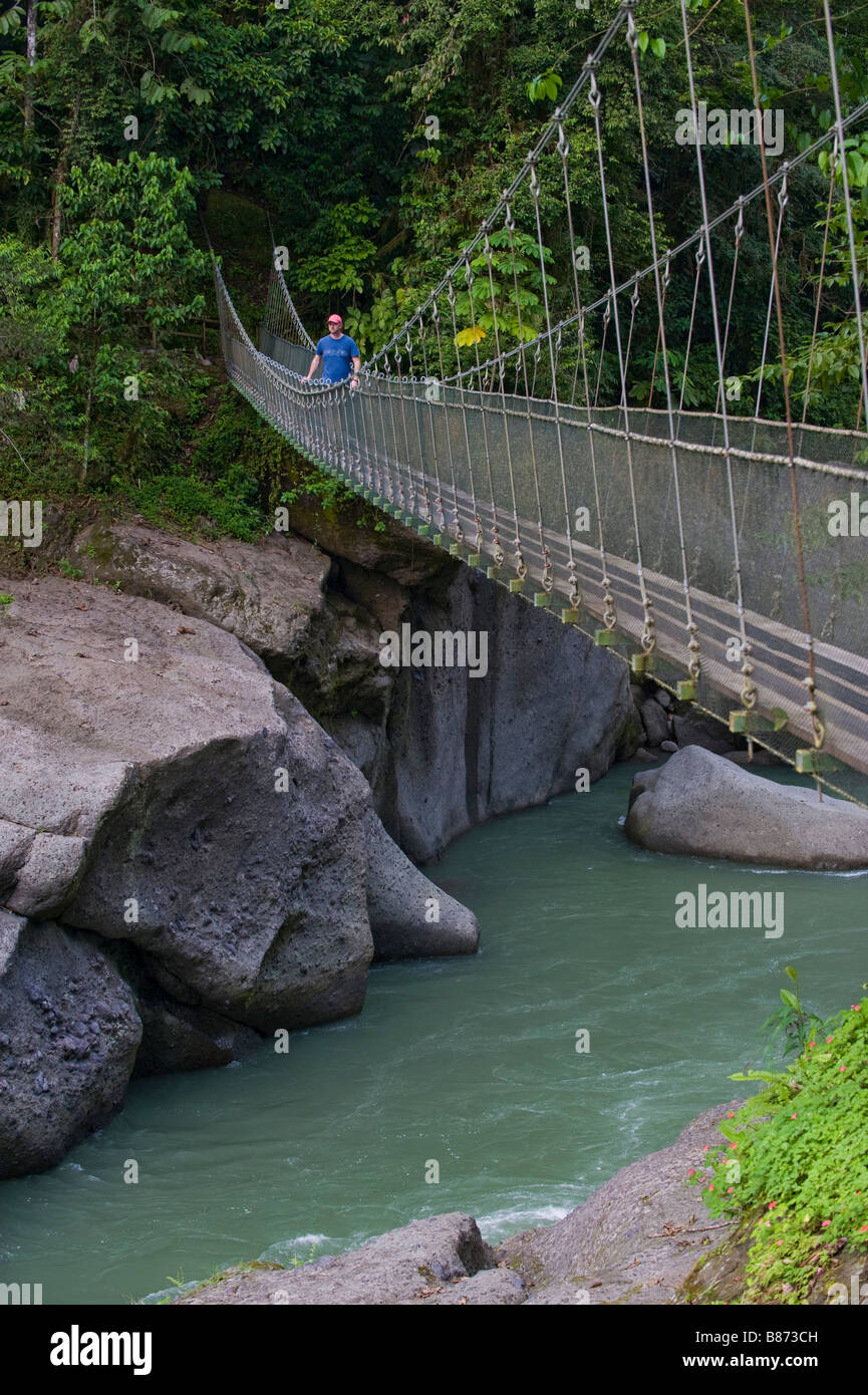 Mittelamerika, Costa Rica. Ein Mann geht über die Pacuare Fluss auf einer Hängebrücke. Stockfoto