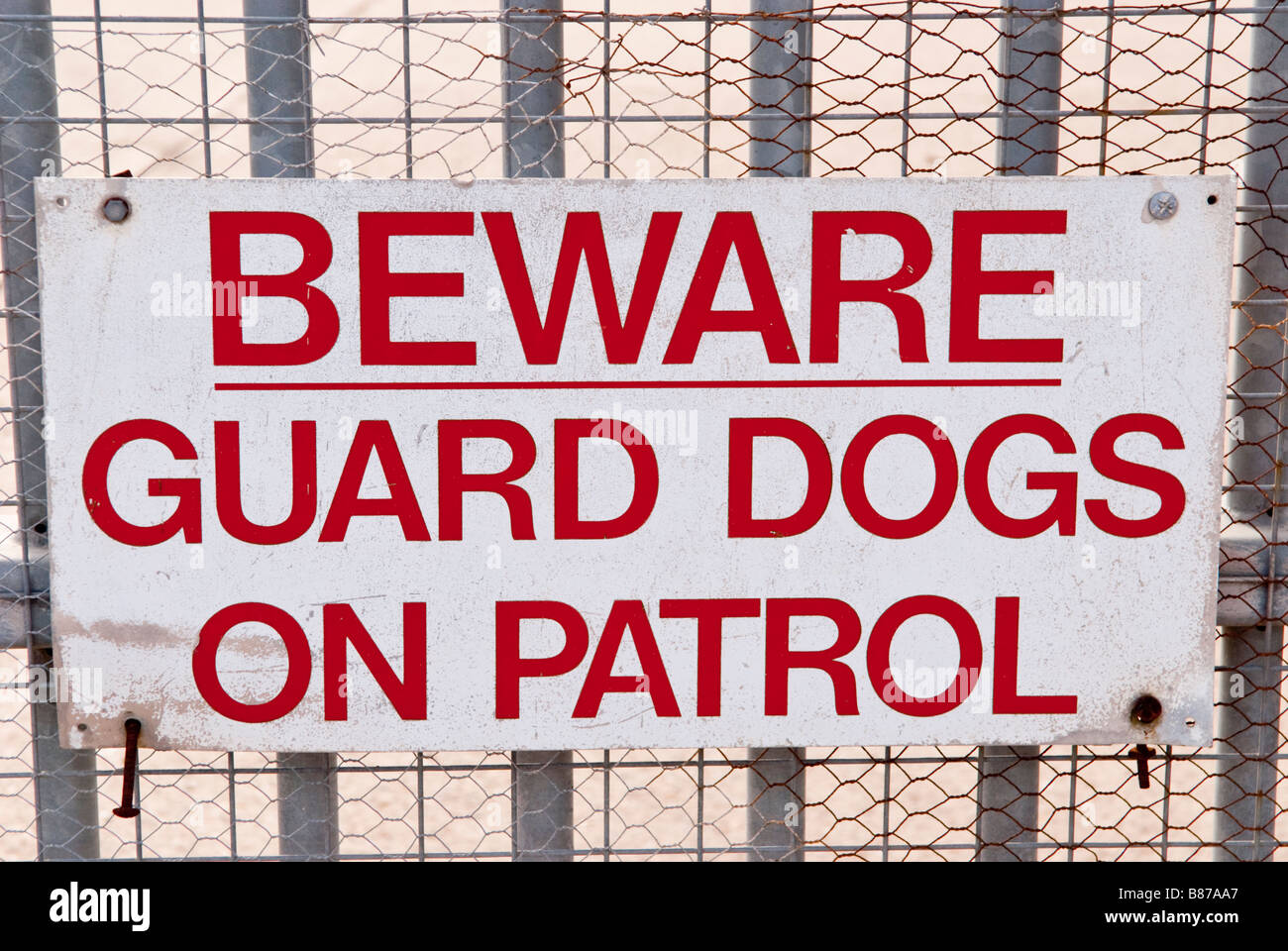Hüten Sie sich vor Wache, die Hunde auf Patrouille am Zaun in Geschäftsräumen zu unterzeichnen Stockfoto