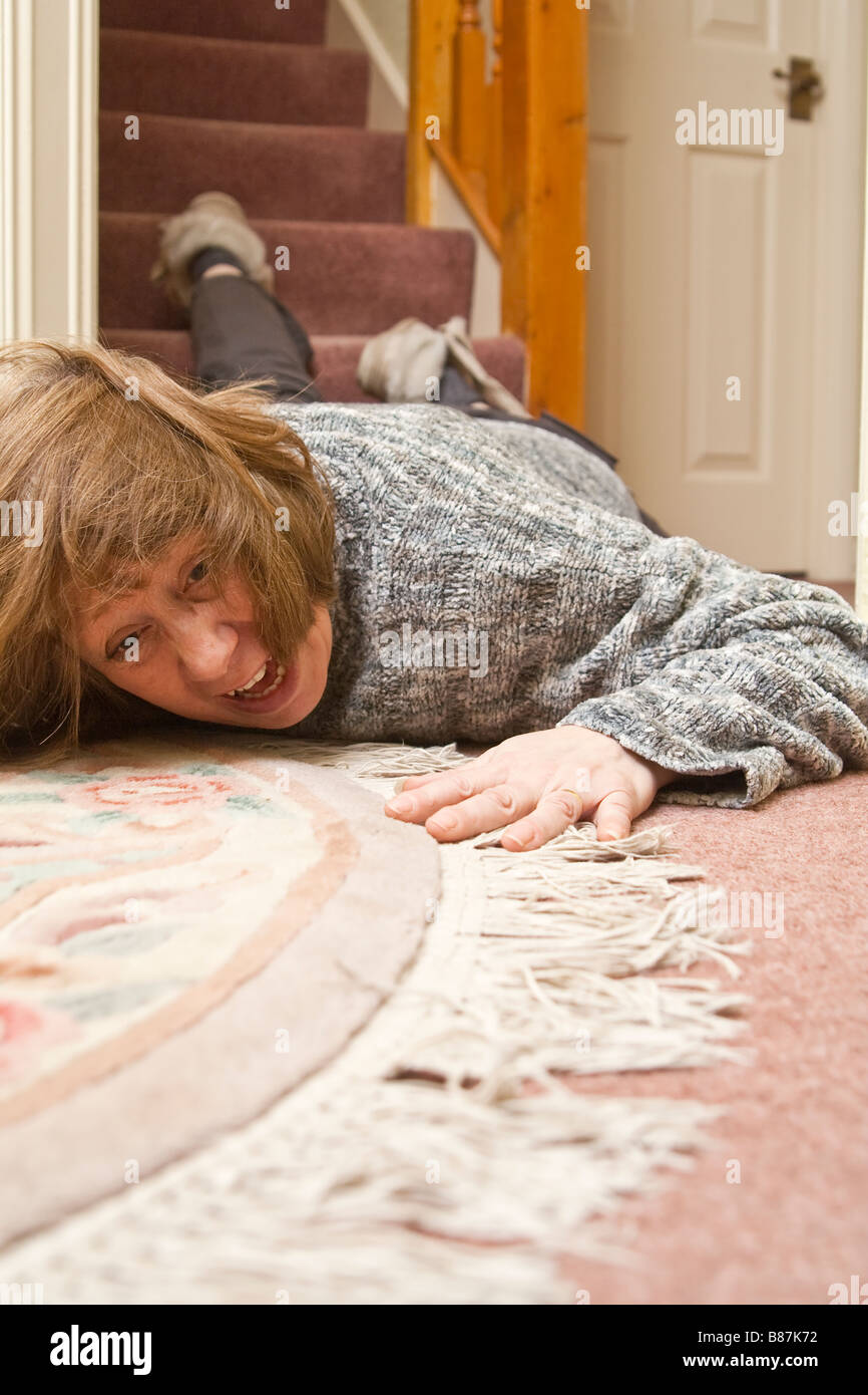 Eine Frau auf dem Boden liegend nach einem Sturz die Treppe hinunter. Stockfoto