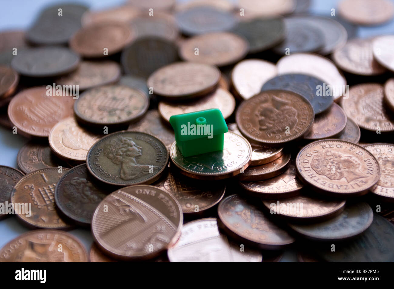 viele Pfennige und ein Monopol-Haus Stockfoto