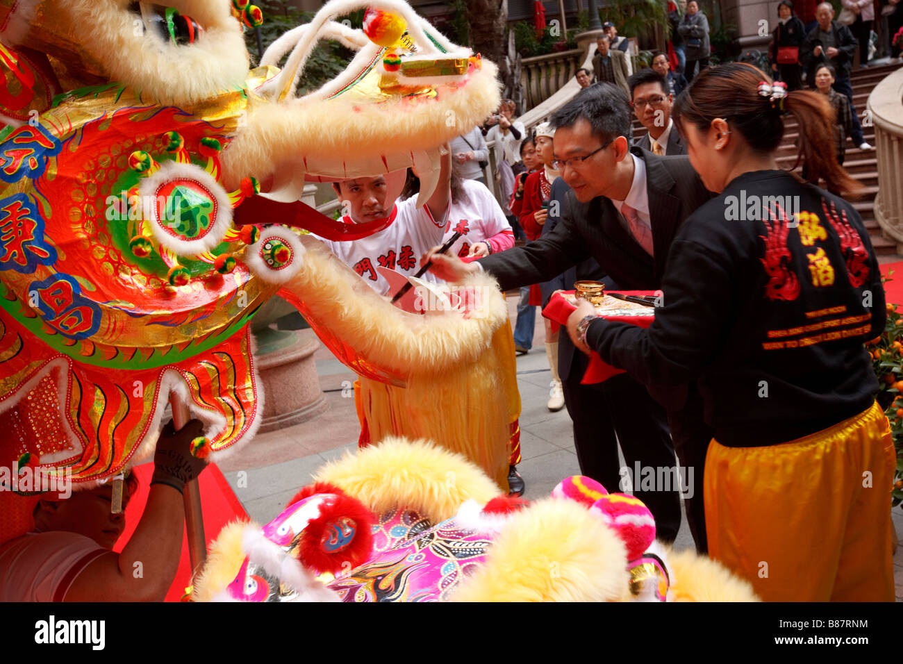 Hong Kong Geschäftsmänner säumen die Augen des mythischen Löwen vor einem traditionellen Löwentanz. Stockfoto