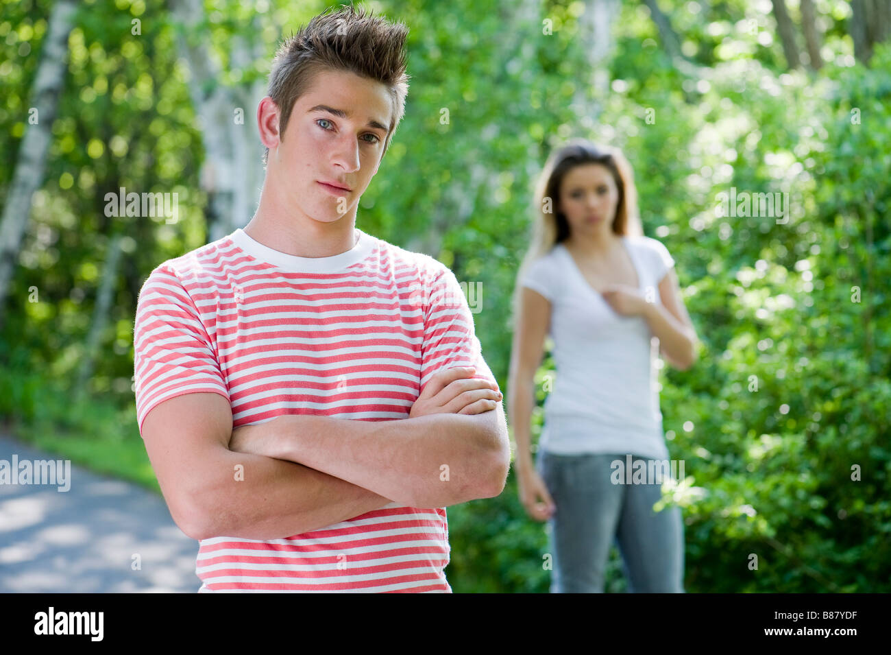 Ein Portrait eines jungen Mannes mit seiner Freundin im Hintergrund Stockfoto