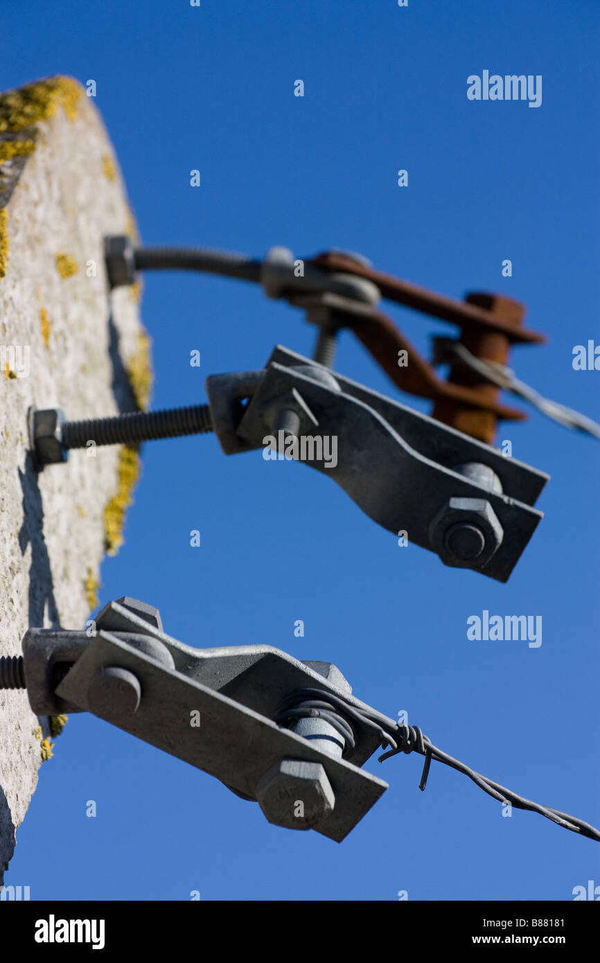 3 verzinkt Stacheldraht Spannern befestigt Pre gegossen konkrete Post gegen blauen Himmel, die rostigen gehört Stockfoto