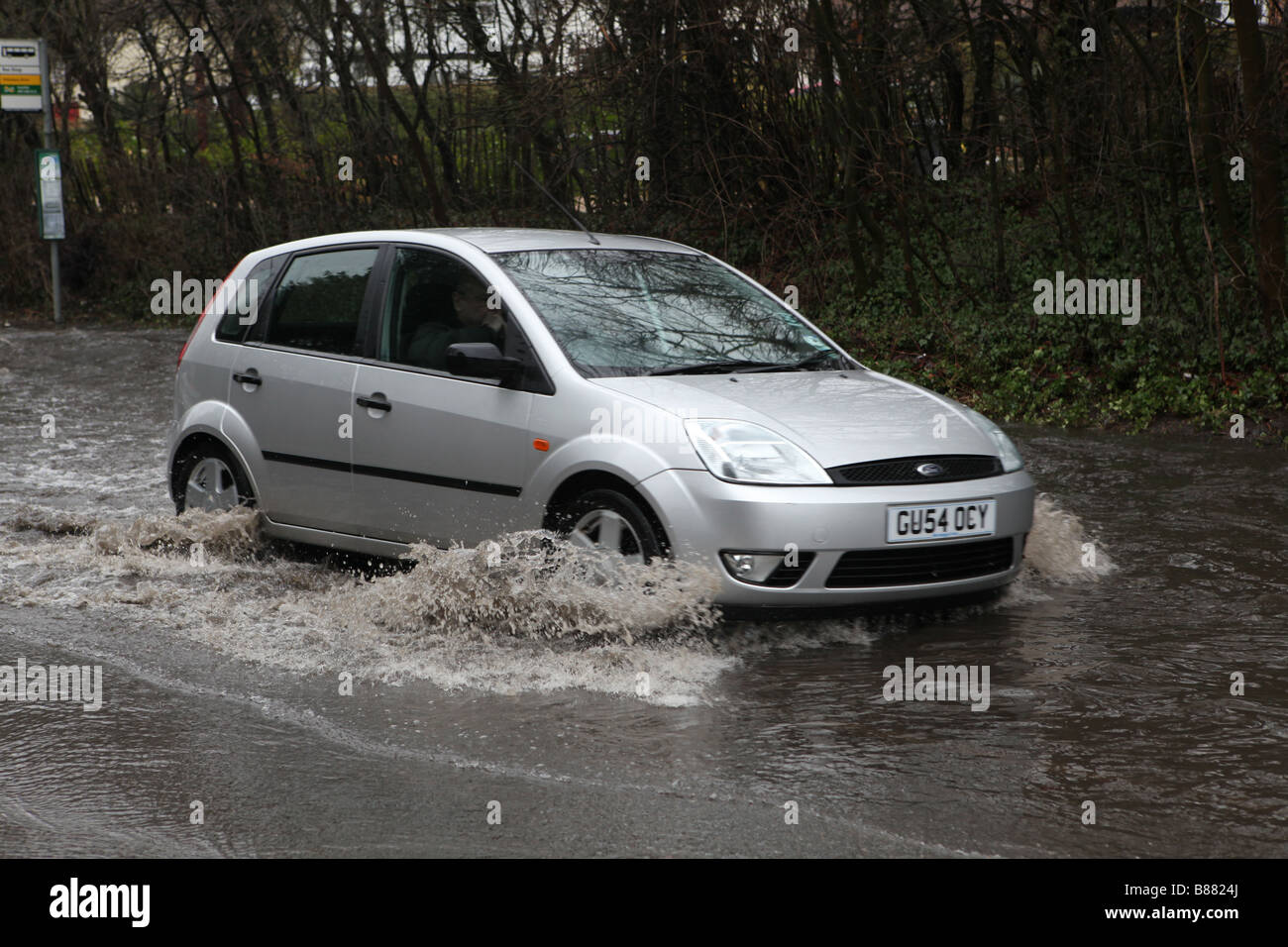 ein Auto fährt durch eine überschwemmte Straße in Harlow, Essex bei Überschwemmungen im Vereinigten Königreich im Februar. das Wasser steigt so weit wie die bumpe Stockfoto