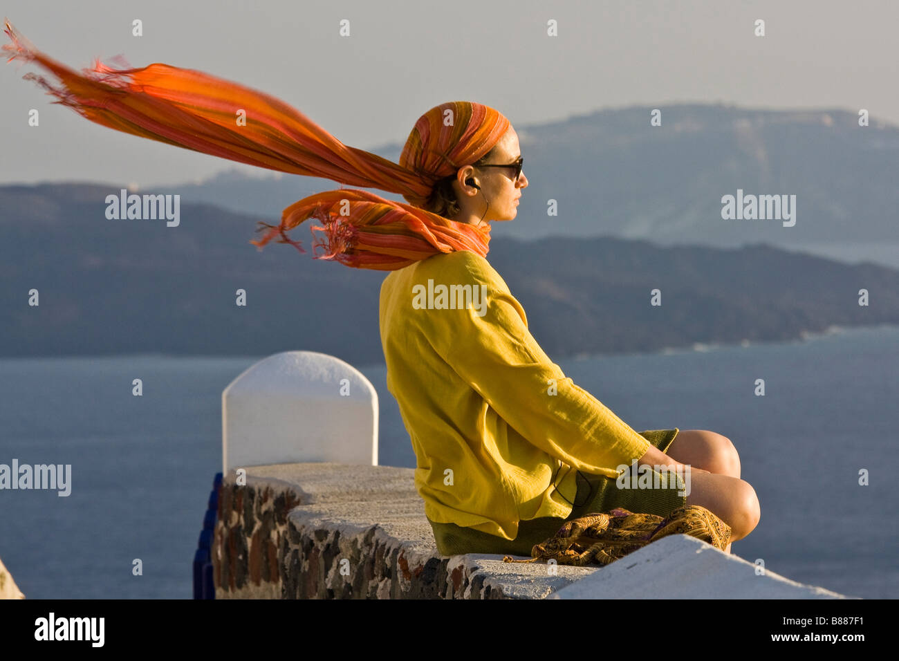 Mädchen sitzen im Wind bei Sonnenuntergang Oia Santorini Kykladen Griechenland Stockfoto
