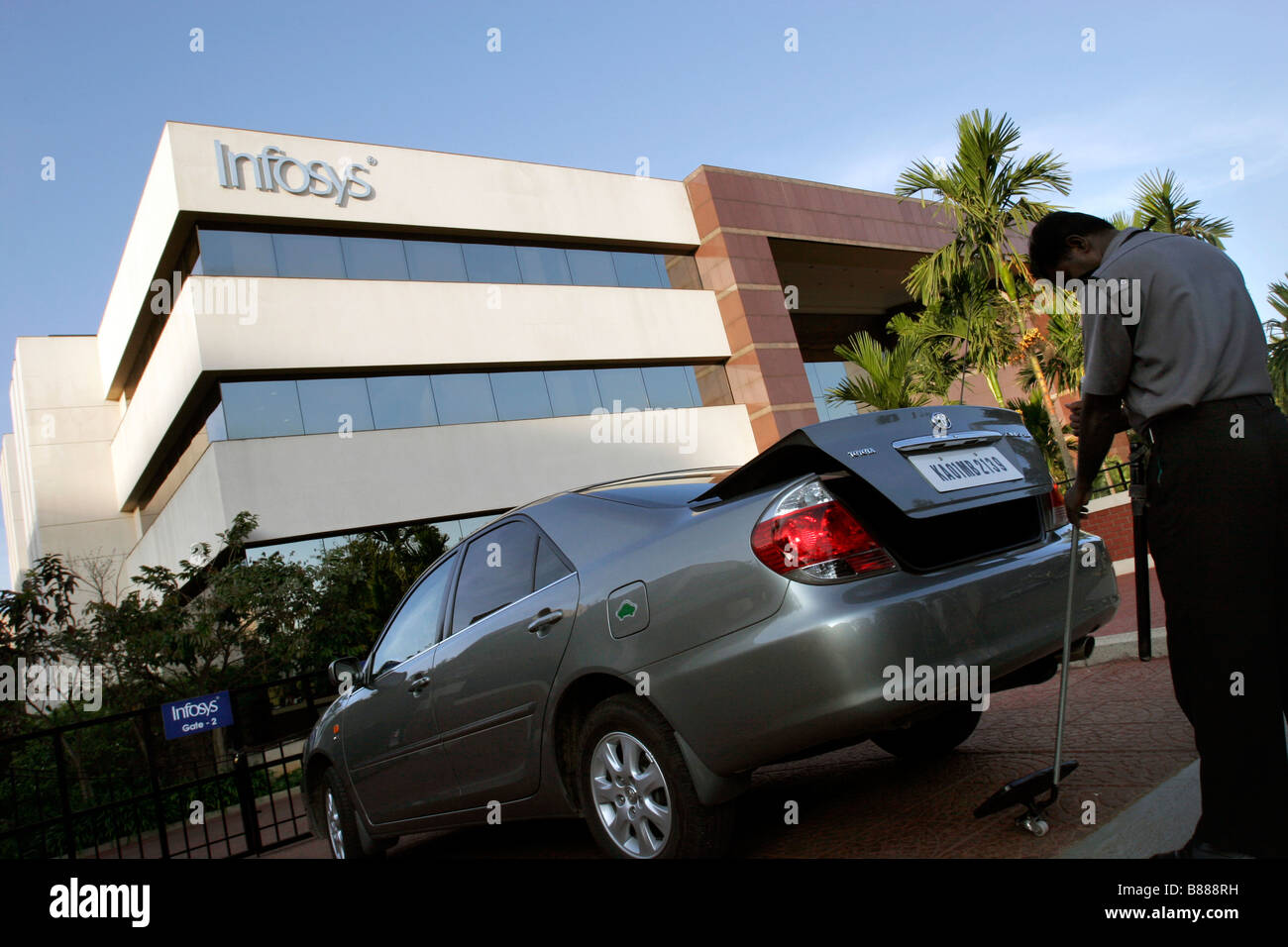 Ein Wachmann prüft ein Auto für Sprengstoff in einem der Einfahrtstore, Infosys-Hauptsitz in Bangalore in Indien Stockfoto