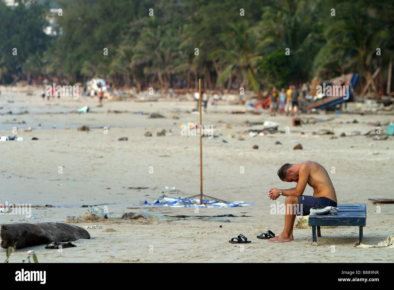 Ein Mann sitzt allein am Patong Beach, Insel Phuket, Thailand am Tag nach dem Tsunami 26. Dezember 2004. Stockfoto