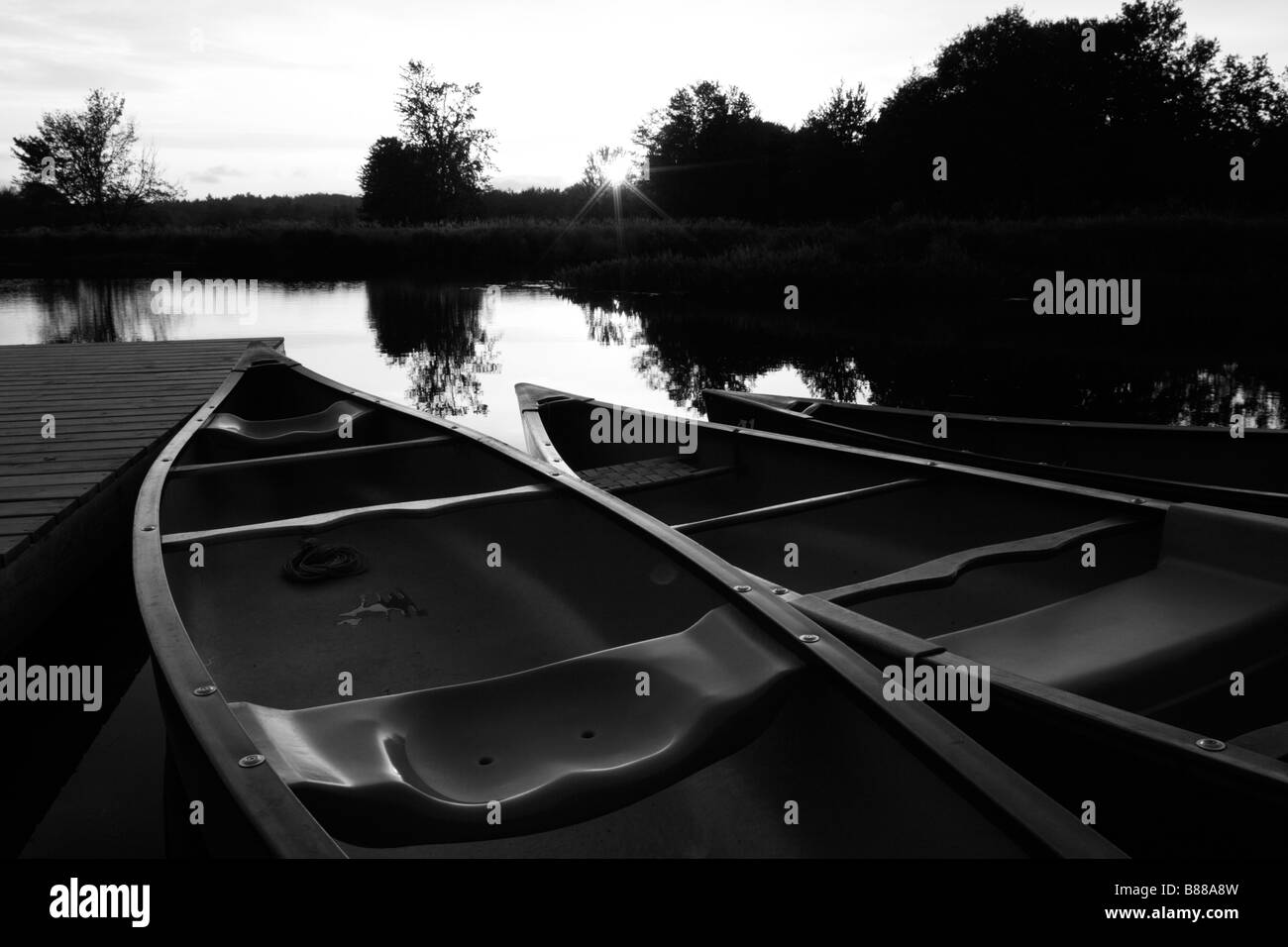 Kanus in einem Fluss bei Sonnenuntergang in schwarz / weiß Stockfoto