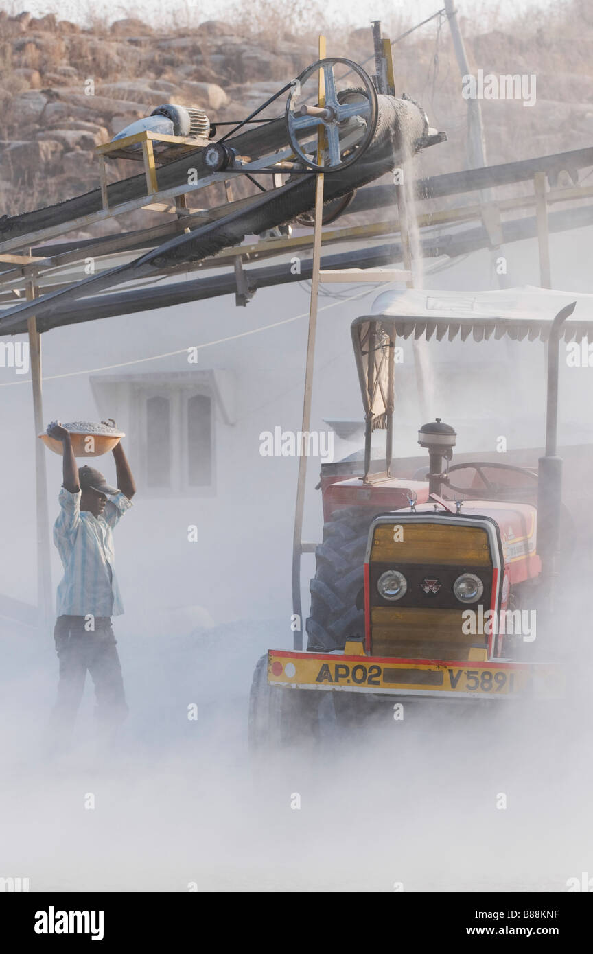Indische Männer setzen Stein in einen Anhänger, umgeben von Staub, ungeschützt, an einem Stein Quetschungen funktioniert. Andhra Pradesh, Indien Stockfoto