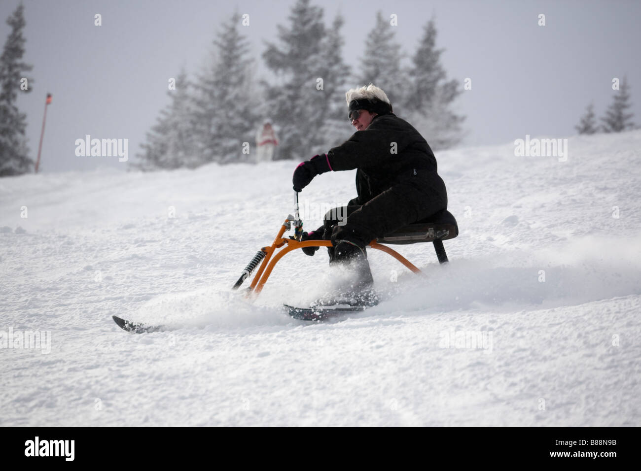 Eine Frau, die auf einem Schnee Scooter bergab eine schneehang Piste. Rauris Österreich Europa Stockfoto