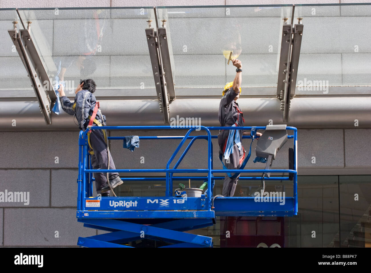Aufrecht erhöhte Arbeitsplattform mit zwei Männern Glasreinigung Stockfoto