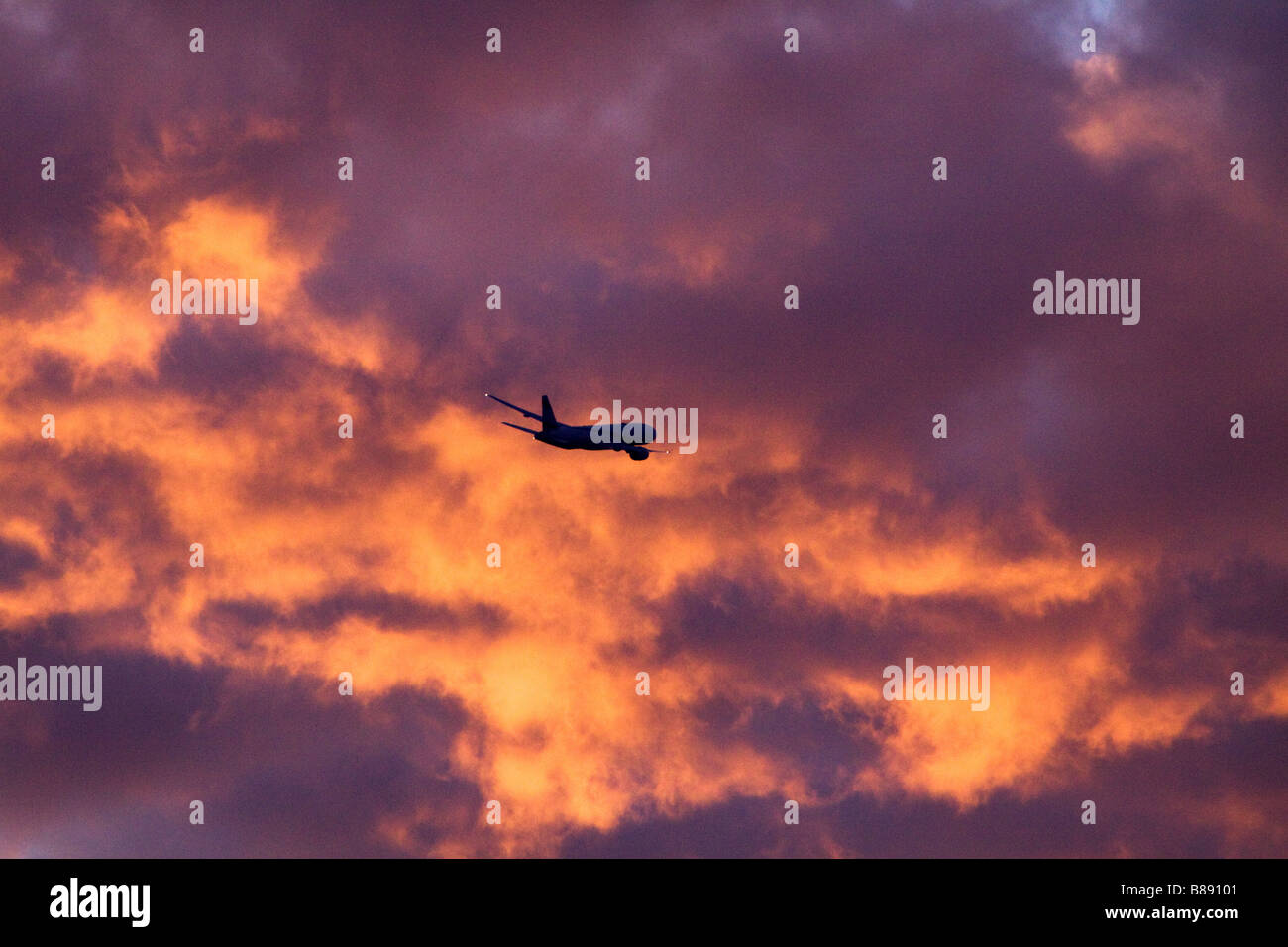 Kommerziellen jet-Flugzeug bei Sonnenuntergang in Richtung dramatisch feurigen Wolken Stockfoto