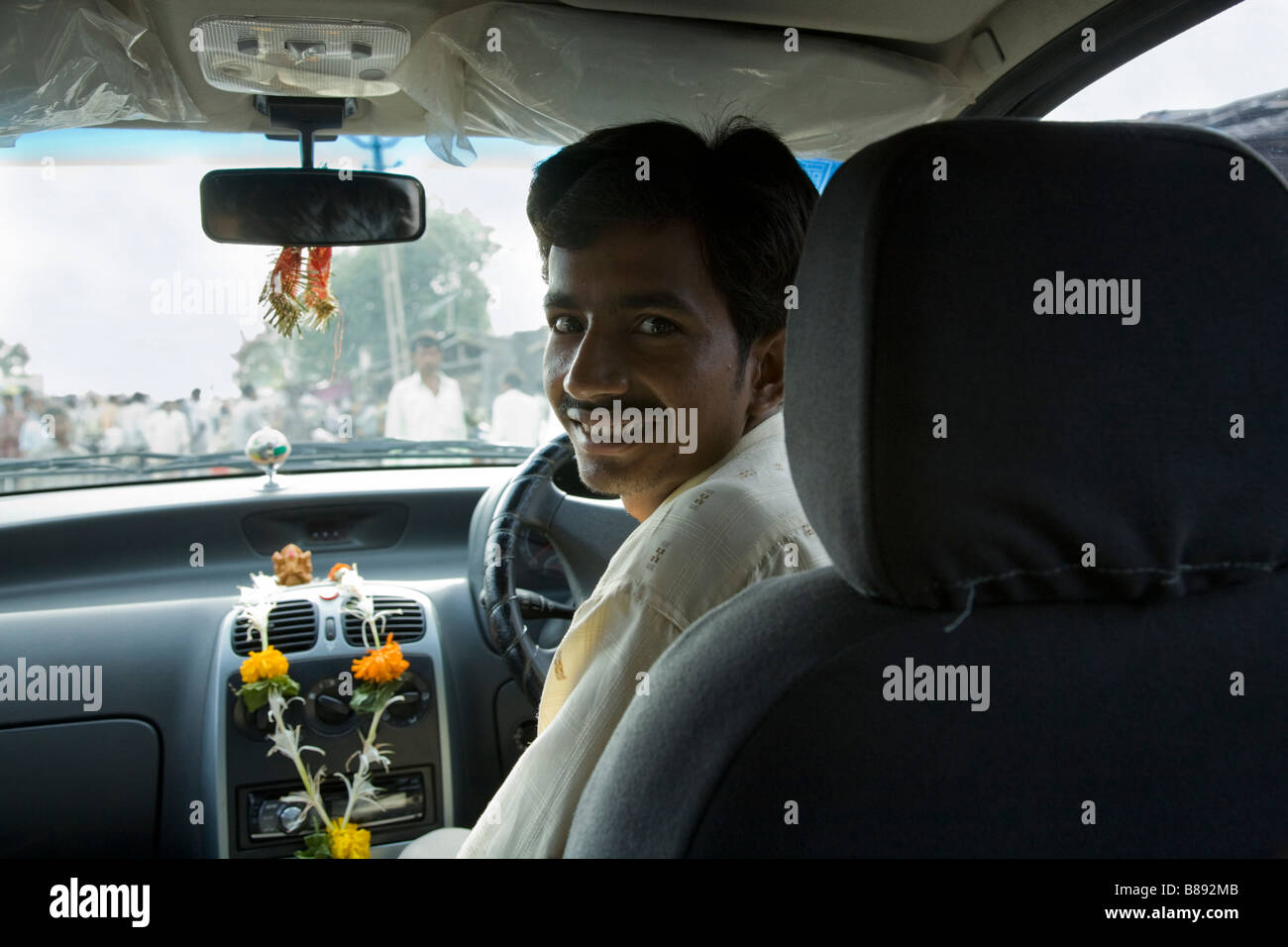 Indische Autofahrer / Fahrer lächelnd am Rücksitz Passagier; Toran Girlanden aus Ringelblumen sind ein Hindu Götter anzubieten. Surat, Indien Stockfoto