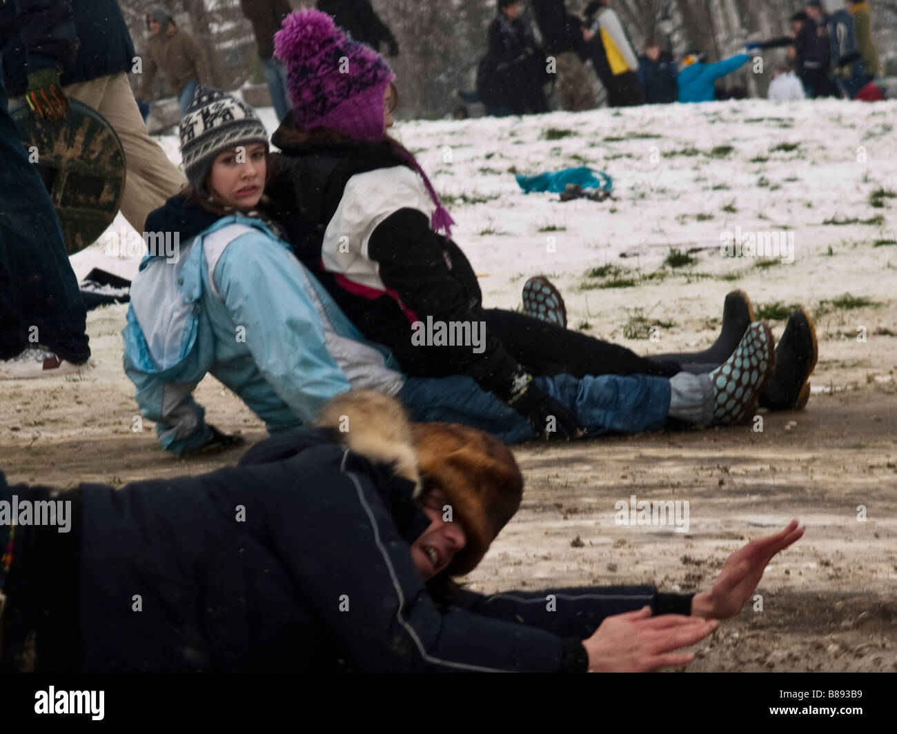 Frau zieht ein Gesicht, als Mann Schlitten fällt Stockfoto