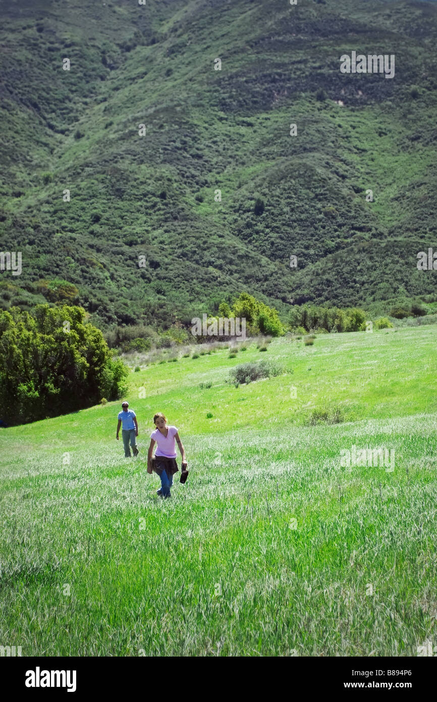 Zwei weibliche Wanderer zu Fuß durch ein grünes Feld in Kalifornien Stockfoto