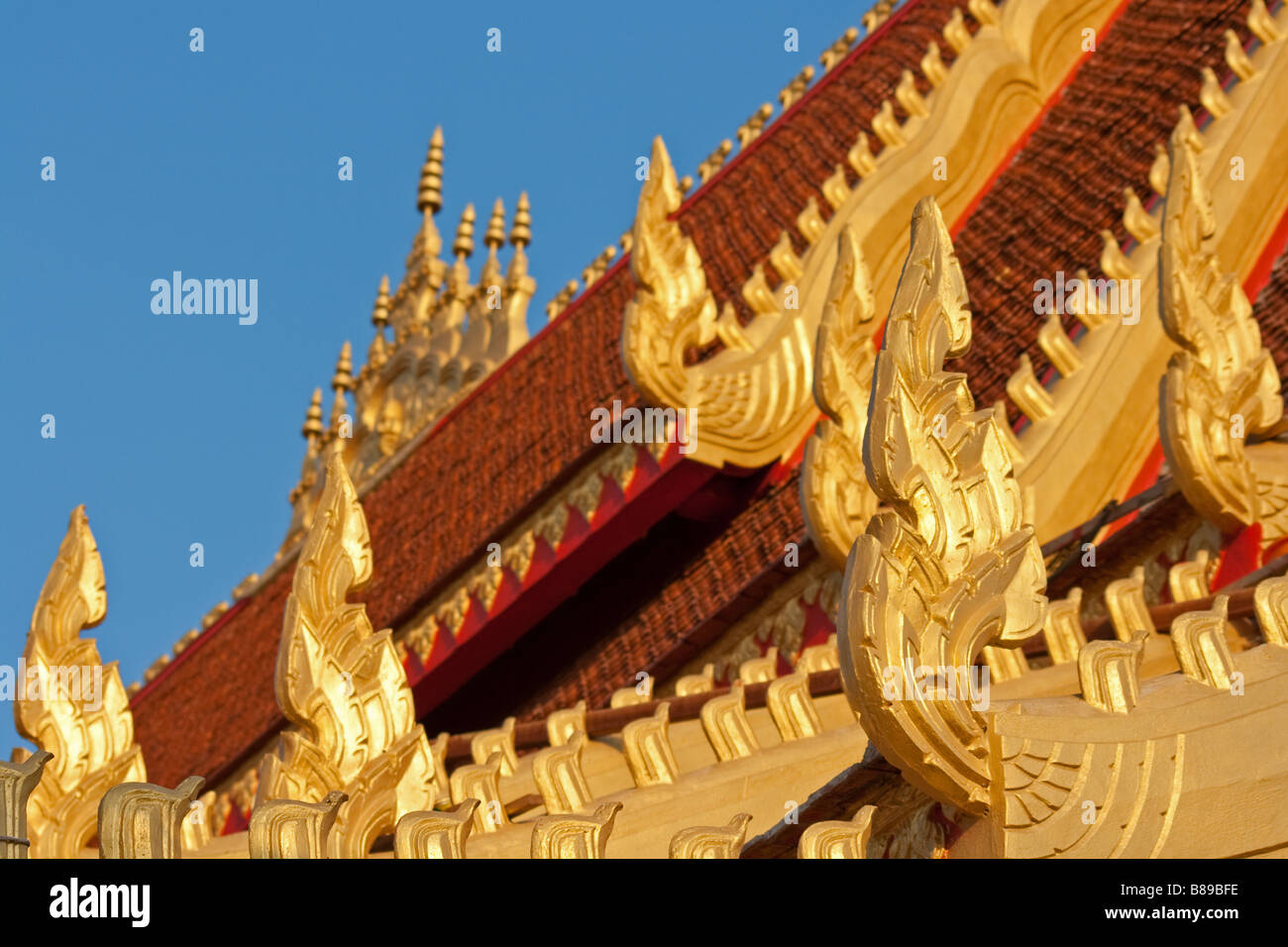 Lebendige und farbenfrohe Dach des buddhistischen Tempel oder Wat lackiert in Gold, mit Terrakotta-Dach-Fliesen schmücken die Gebäudearchitektur in Savannakhet, Laos Stockfoto