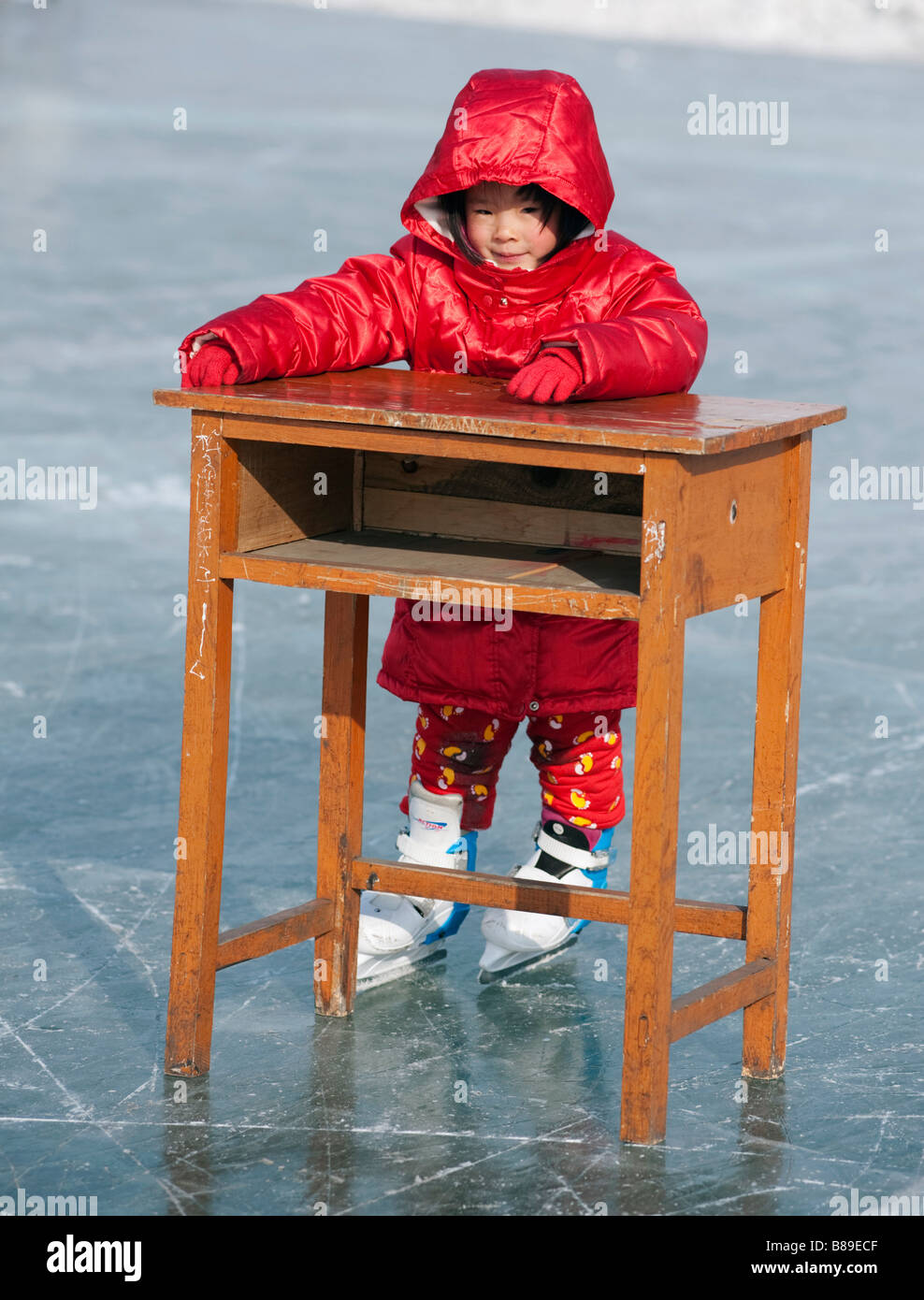 Junge Chinesin mit hölzernen Schreibtisch Skaten lernen zu helfen, Balance auf gefrorenen Fluss Songhua River Harbin China 2009 Stockfoto