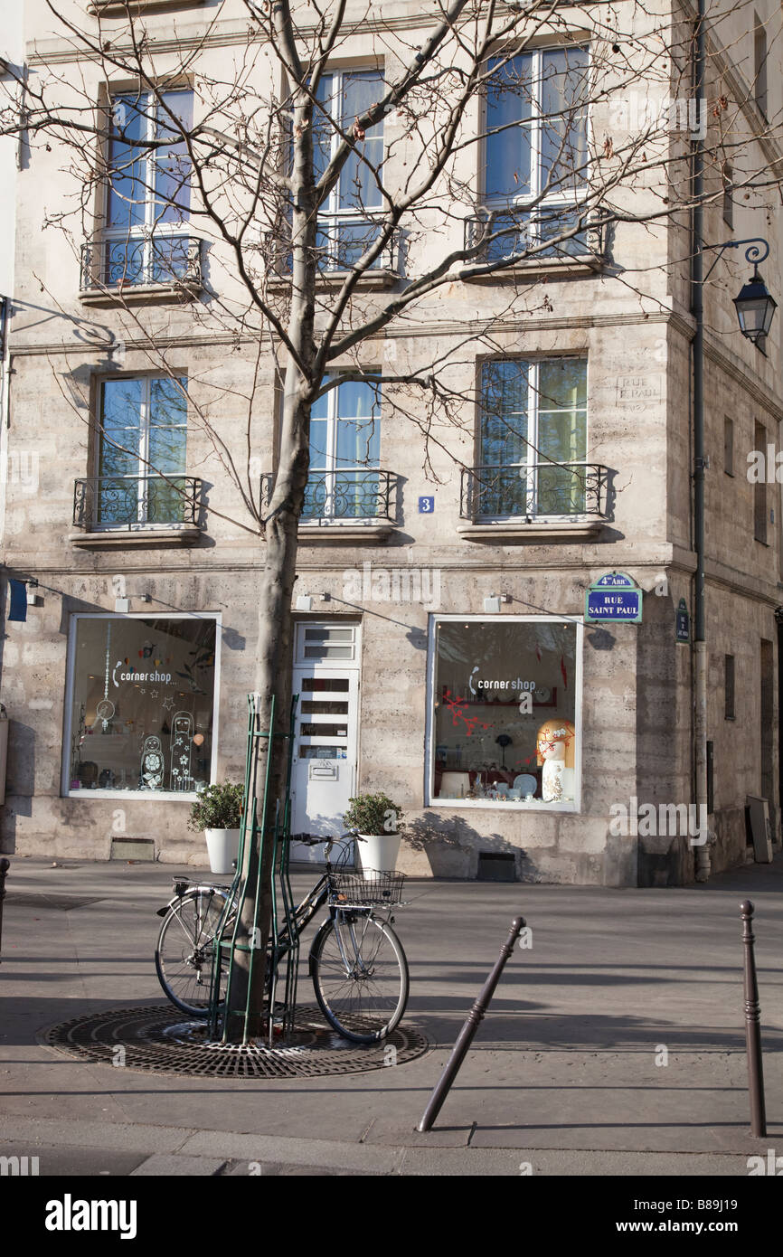 Fahrrad angekettet an Baum vor Shop auf typisch Paris street Stockfoto