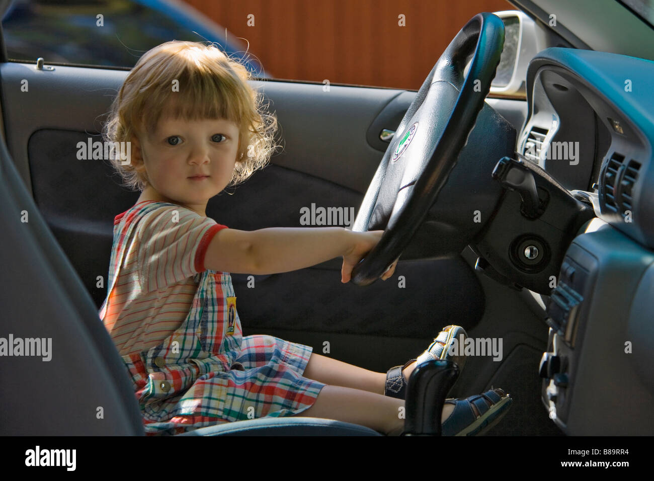 JUNGE 2 JAHRE VORGIBT, EIN AUTO ZU FAHREN Stockfoto