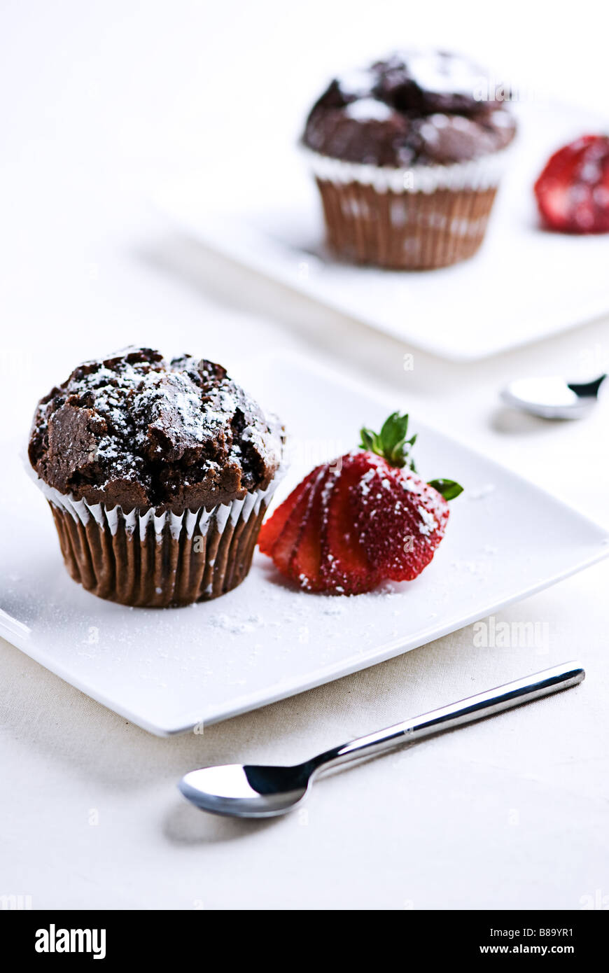 2 Platten mit Schokoladen-Muffins mit einer Erdbeere garniert Stockfoto