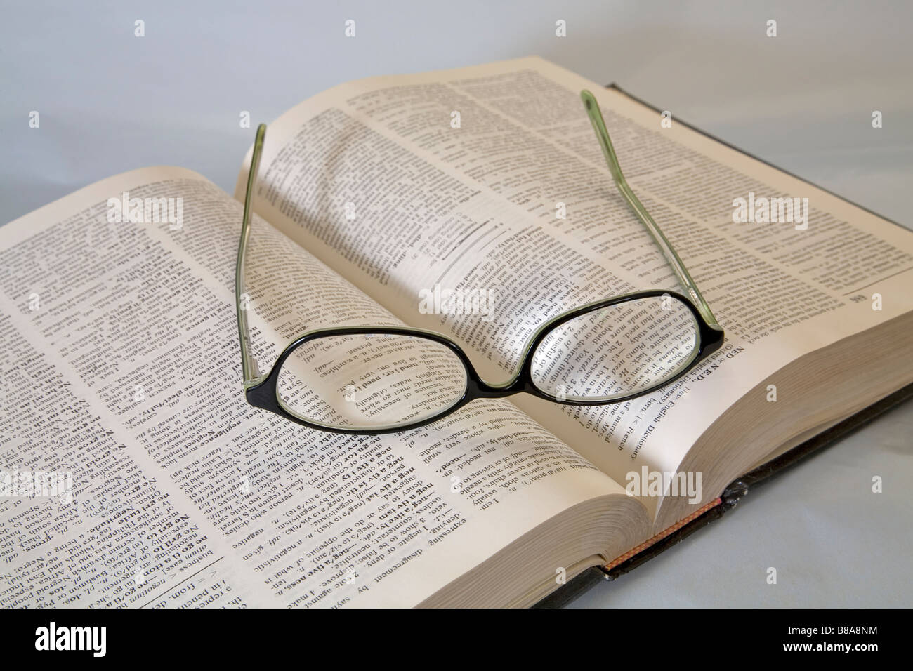 Ein paar gemeinsame Brillen oder Brillen liegen auf einem offenen Wörterbuch lesen Stockfoto