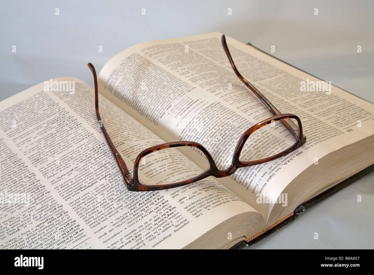 Ein paar gemeinsame Brillen oder Brillen liegen auf einem Wörterbuch lesen Stockfoto