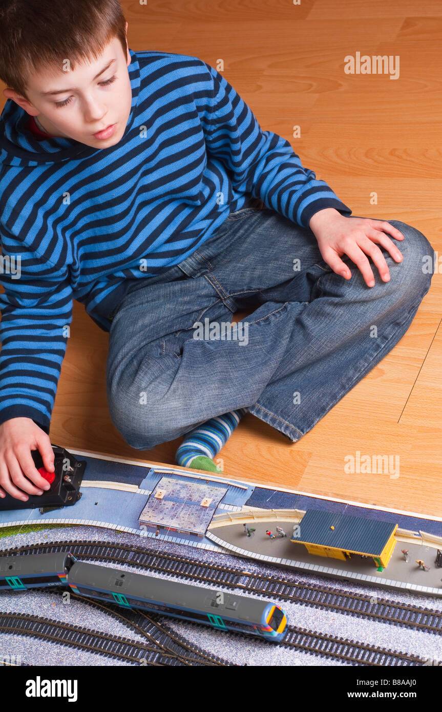 Kleiner Junge spielt mit Modell Spielzeug elektrische Eisenbahn Set in Oo Messgerät mit Motoren von Hornby und Bachmann Modelleisenbahnen Stockfoto