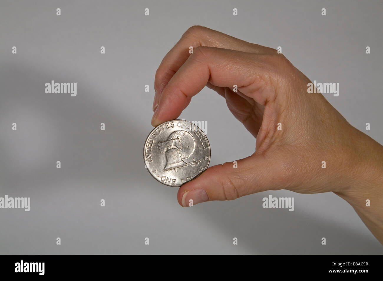 Jemand hält eine US-Silber-Dollar-Münze mit einem Bild von der Liberty Bell zwischen ihren Fingern Stockfoto