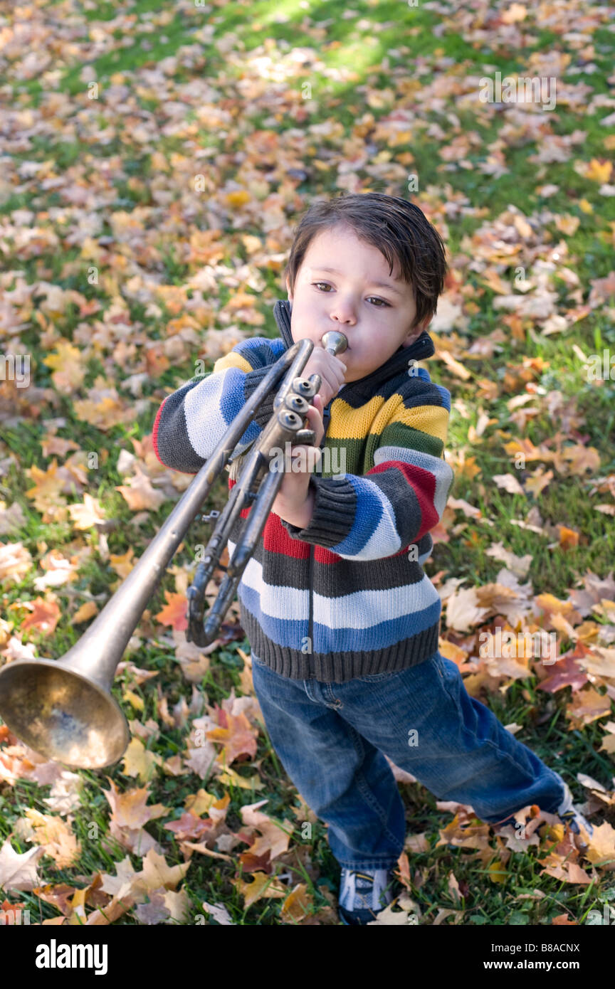 Drei Jahre alter Junge spielt mit seiner Trompete außerhalb an einem Herbsttag Stockfoto