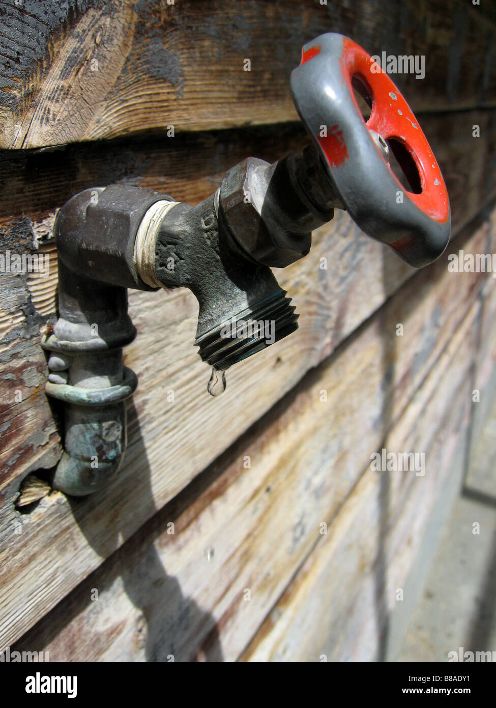Ein Wasserhahn tropft und vernachlässigter veranschaulicht die Bedeutung der Instandhaltung für Gewässerschutz. Stockfoto